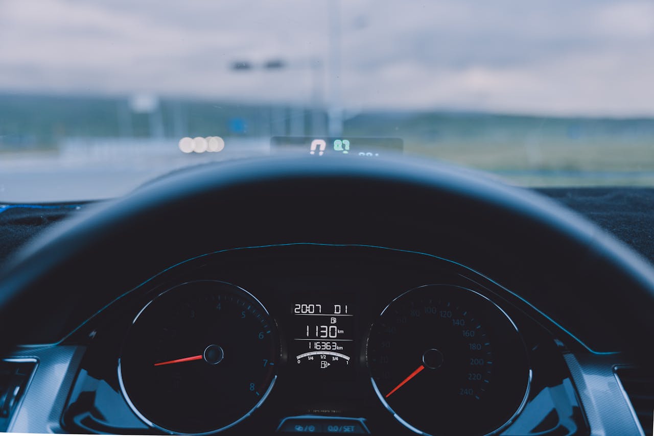 View from inside a car showing dashboard and steering wheel on an open road.